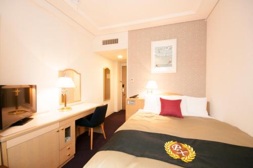 八戸市にあるグランパークホテルパネックス八戸のベッドとデスクが備わるホテルルームです。