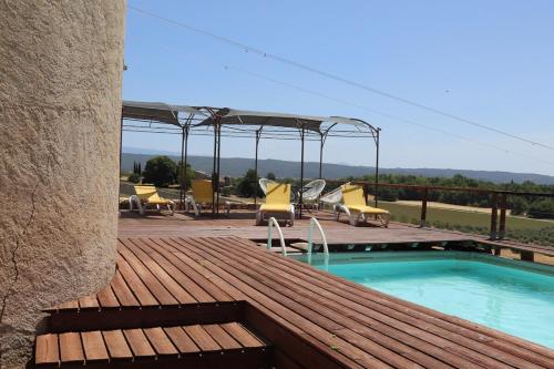 a deck with chairs and a swimming pool on a building at La Petite Grande in Lurs