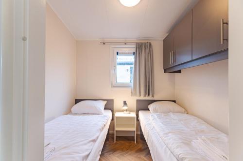 two beds in a room with a table and a window at Duinhoeve chalet Schelp in Burgh Haamstede