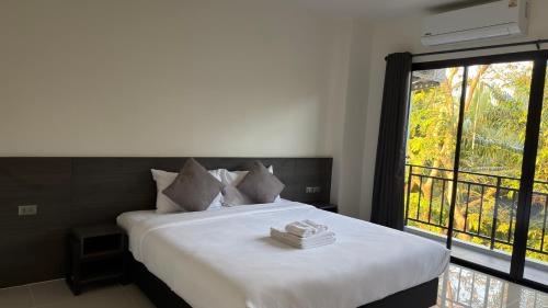 a bedroom with a bed with a large window at A House Thalang เอ เฮ้าส์ ถลาง in Thalang