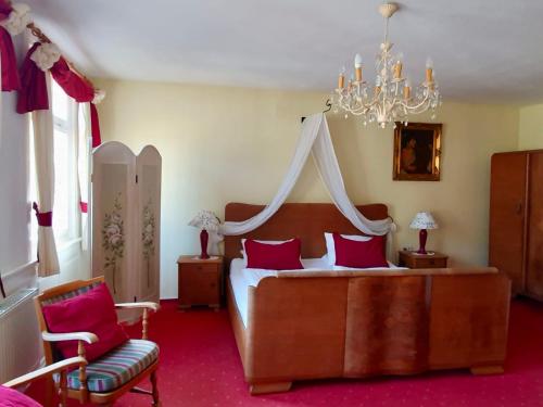 a bedroom with a bed with red pillows and a chandelier at Gasthof Sonne in Schiltach