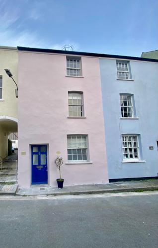 a pink and white house with a blue door at Little Monmouth 4 bedroom cottage, Old town Lyme Regis, dog friendly and parking in Lyme Regis