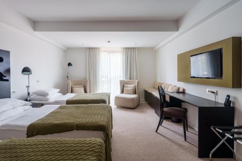 ein Hotelzimmer mit drei Betten und einem Schreibtisch in der Unterkunft Hotel Palisad in Zlatibor