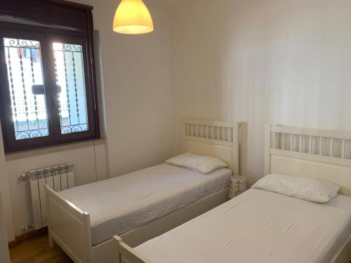 two beds in a small room with a window at Pescasseroli center Case del Parco in Pescasseroli