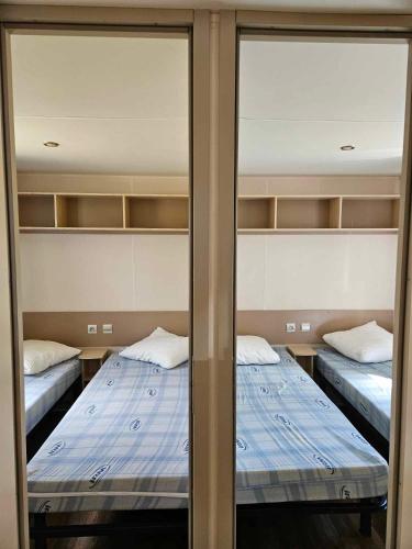two beds in a room with glass doors at camping de l'or bleu in Barrême