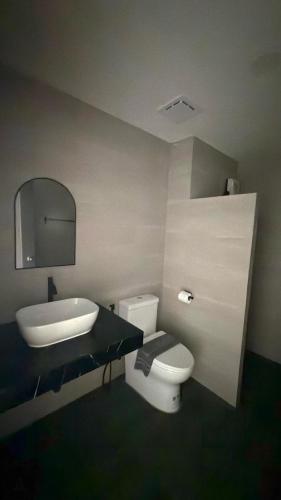 a bathroom with a sink and a toilet and a mirror at A House Thalang เอ เฮ้าส์ ถลาง in Thalang
