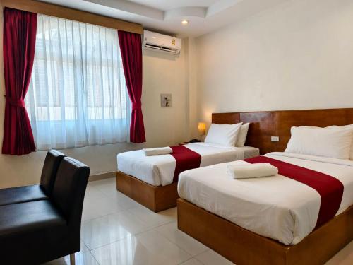 a hotel room with two beds and a chair at Zing Resort & Spa in Pattaya South