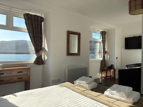 a bedroom with a bed and a desk and windows at Argyll Hotel in Ullapool