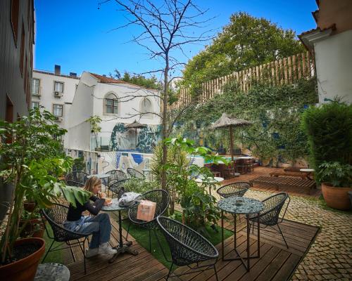 a woman sitting at a table in a garden at Secret Patio Lisbon in Lisbon