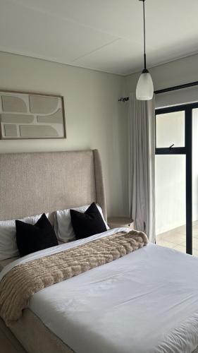 a bedroom with a large white bed with black pillows at Elara in Sandton