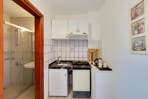 a small white kitchen with a sink and a shower at NATURELLA APART HOTEL in Kemer