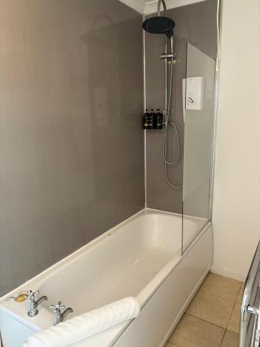 a white bath tub with a glass shower stall at Argyll Hotel in Ullapool