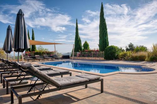 a swimming pool with lounge chairs and umbrellas at Casa Rosa - Heated Pool & Sea Views in Loulé