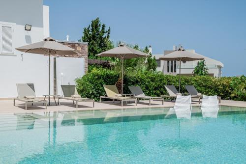 a swimming pool with chairs and umbrellas at J&K Villa in Kalithies