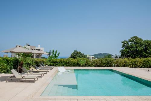 a swimming pool with lounge chairs and an umbrella at J&K Villa in Kalithies