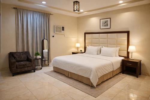 a bedroom with a large bed and a chair at Roaa Apartments شقق مخدومة in Al Qunfudhah