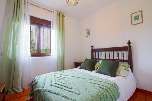 a bedroom with a bed with green pillows and a window at La balcon de Sanfer in Santillana del Mar