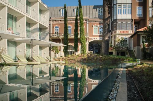 a pool of water with chairs and an umbrella at One Shot Palácio Cedofeita in Porto