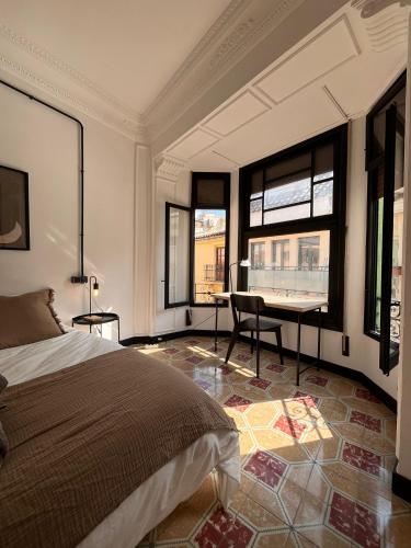 a bedroom with a bed and a desk and windows at Terrazas de la Catedral II in Castellón de la Plana