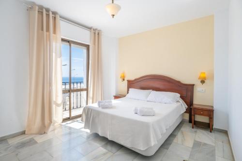a bedroom with a bed and a large window at Apartahotel Playamaro by Dorobe in Maro