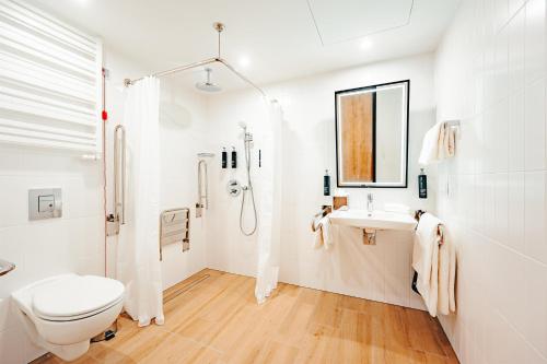 a white bathroom with a toilet and a sink at Hilton Garden Inn Radom in Radom