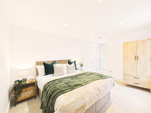 a white bedroom with a large bed and a dresser at NEW Artisan Apartment by Signature Stays - Modern - Spacious - Parking in Cheltenham