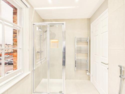 a glass shower in a bathroom with a window at NEW Artisan Apartment by Signature Stays - Modern - Spacious - Parking in Cheltenham