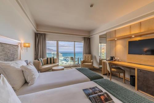 a hotel room with a large bed and a television at Pestana Carlton Madeira Ocean Resort Hotel in Funchal