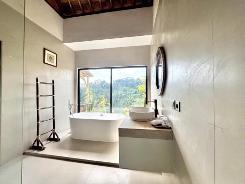 a bathroom with a tub and a sink and a window at Jungle Valley Villas in Susut