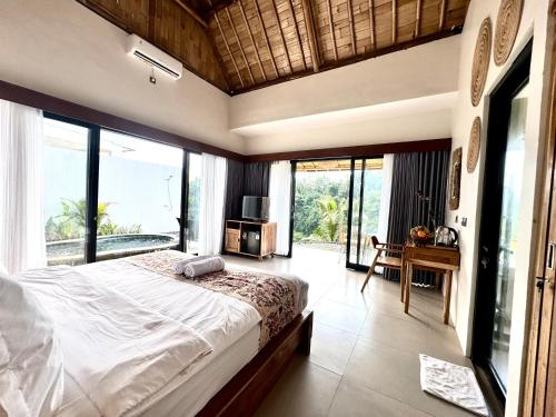 a bedroom with a large bed and large windows at Jungle Valley Villas in Susut