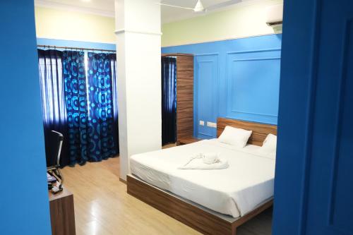 a bedroom with a bed with a blue wall at Royal Service apartment - KK Nagar Madurai in Madurai