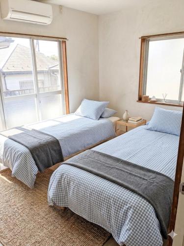 two beds in a room with a window at Blue moon house miyama in Funabashi
