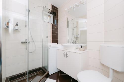 a white bathroom with a sink and a shower at Sovata Apartment in Sovata