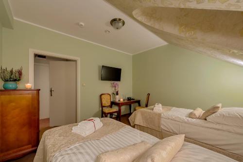 a room with two beds and a table with a television at Hotel Dwór Fijewo in Golub-Dobrzyń