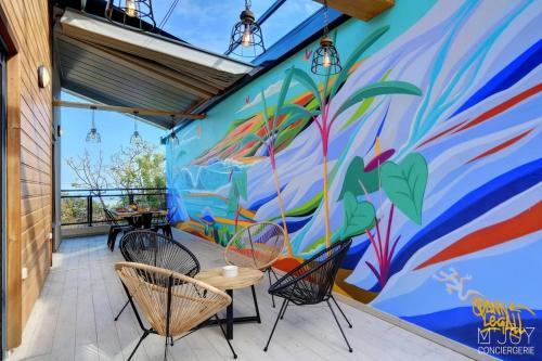 a mural on the side of a building with chairs at TIGOUYA - House of 135m - 2 bedrooms Jacuzzi in Stella Matutina