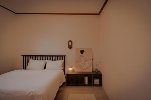 a bedroom with a bed and a table with a lamp at 퍼즈스테이 Pause Stay in Chuncheon