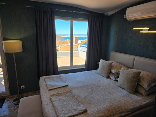 a bedroom with a large bed and a large window at The White House Guest House in Nesebar