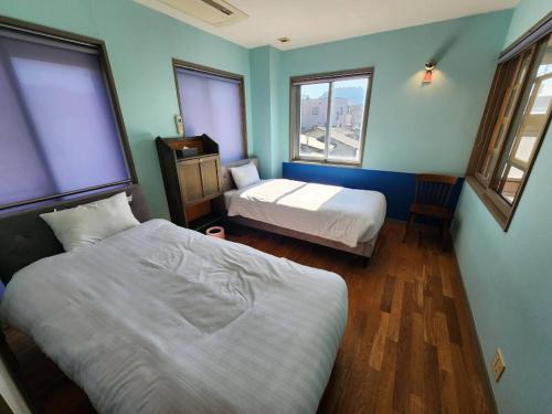 a bedroom with two beds and two windows at Takayama Fortune-inn in Takayama