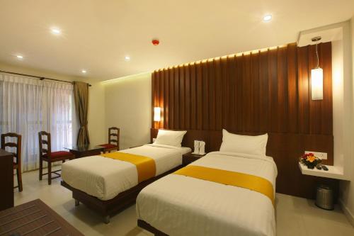 a hotel room with two beds and a desk at Hotel Indraprastha Thiruvananthapuram in Trivandrum
