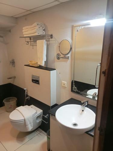 a bathroom with a sink and a toilet and a mirror at Hotel Indraprastha Thiruvananthapuram in Trivandrum