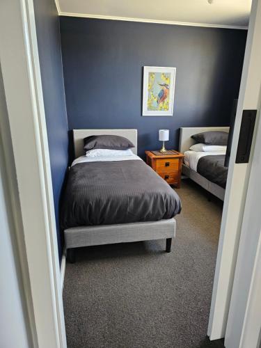 a bedroom with two beds and a blue wall at Livingstone Retreat in Hokitika