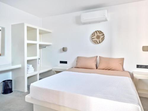 a white bedroom with a bed and a clock on the wall at Cozy Hideaway Room with Private Jacuzzi in Krotiri