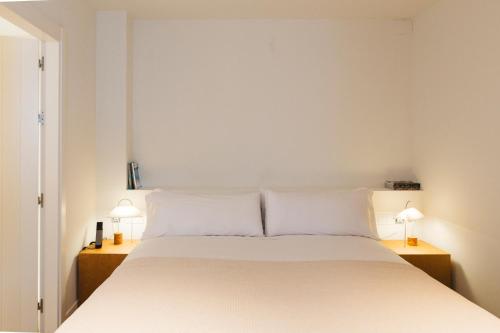 a bedroom with a large white bed with two lamps at Casa Teva Rooms Sevilla in Seville