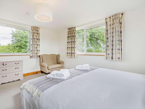 a bedroom with a bed and a chair and two windows at 5 Bed in Dunkeld oc-90585 in Dunkeld