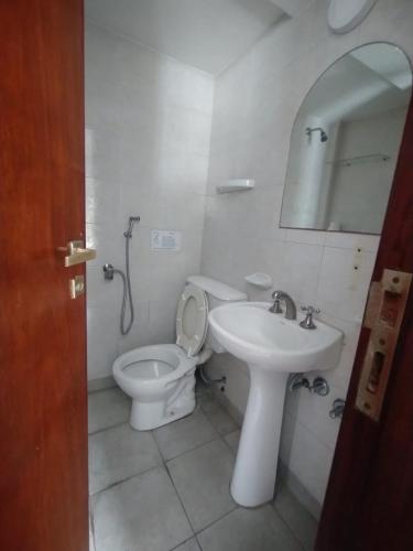 a white bathroom with a toilet and a sink at PASEO GüEMES HOTEL in Salta