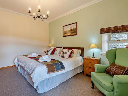 a bedroom with a bed and a green chair at 1 Bed in Edzell oc-ca335 in Edzell