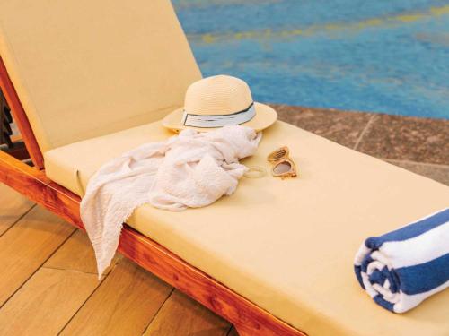 a towel and hat sitting on a chair at Sunday Resort & Spa Manesar by CheckIn, Gurugram in Gurgaon