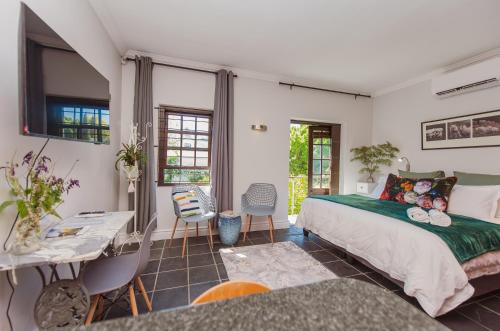 a bedroom with a bed and a desk and chairs at Central Stellenbosch Apartment with secure parking in Stellenbosch