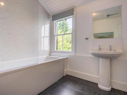 a white bathroom with a sink and a tub and a window at 6 Bed in Keswick oc-sz044 in Braithwaite