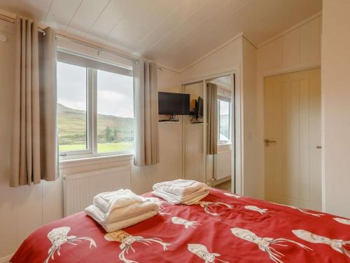 a bedroom with a bed with a red blanket and a window at 2 Bed in Isle Of Skye oc-87578 in Portree